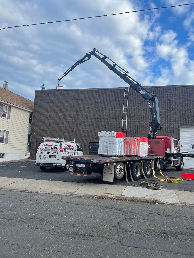 Boom truck delivering roofing material to the roof of a commercial building
