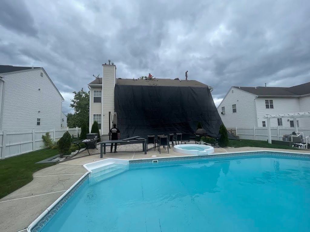 Black catch tarp draped over the rear of a house to keep debris out of the backyard pool
