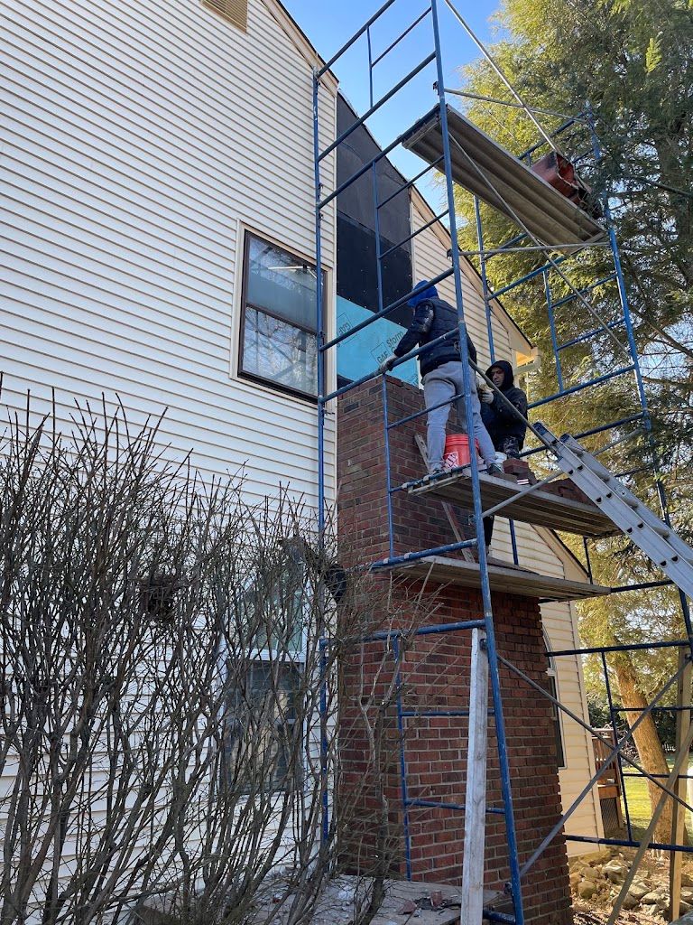 Masons on scaffolding working on the brickwork of a chimney against a house