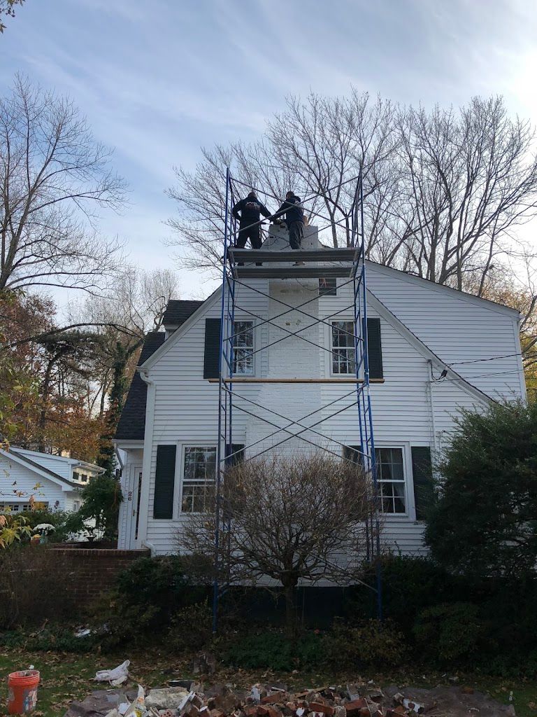 Scaffold tower built against a white colonial home with the crew working on the chimney at the top